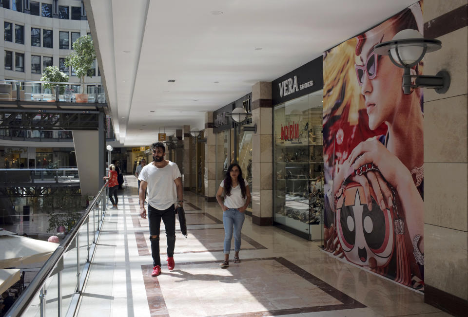 People walk in a shopping mall in Ankara, Turkey, Wednesday, Aug. 15, 2018. Turkey announced increased duties on US products, including cars, tobacco and alcohol, on Wednesday in retaliation to U.S. sanctions and tariffs on Turkey in an on-going feud over the detention of an American pastor.(AP Photo/Burhan Ozbilici)