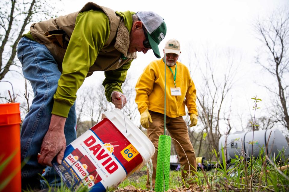 Tim Meyer and Paul Millice volunteer to plant trees Monday, April 22, 2024, at Strasser Woods in Des Moines.