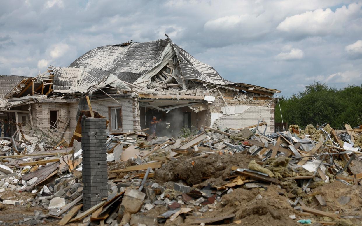 A local resident removes debris from a damaged home