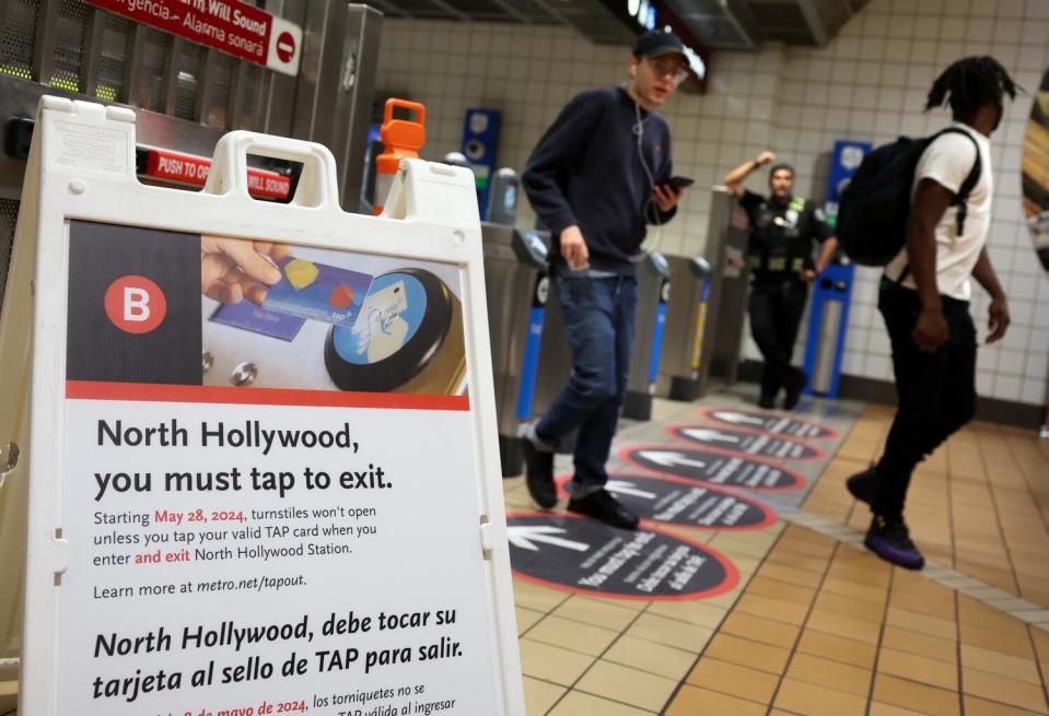 Metro riders pass through turnstiles.