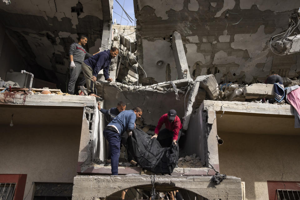 Palestinians carry the body of a woman found under the rubble of a destroyed building following an Israeli airstrike in Rafah, Gaza Strip, on Wednesday, March 27, 2024. (AP Photo/Fatima Shbair)