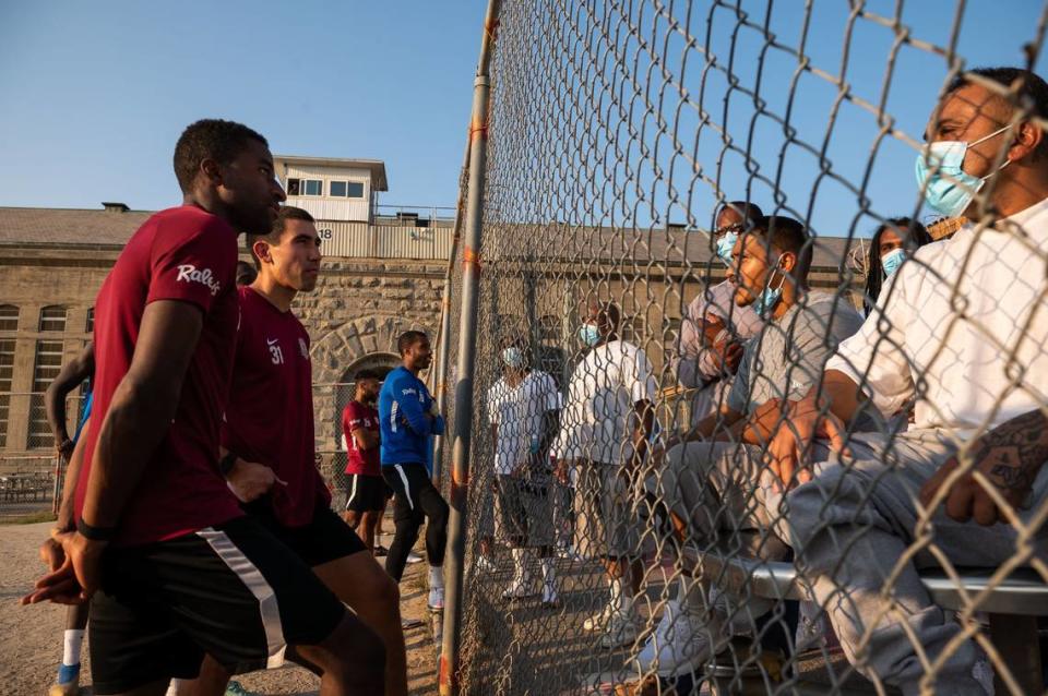 Sacramento Republic FC defender Duke Lacroix, left, and forward Cameron Iwasa a Sacramento native talk soccer and life with Folsom State Prison inmates on Aug. 24, 2021, after a full team practice in the prions yard. Goalkeeper Rafael Díaz, center, talks with other inmates in the background.