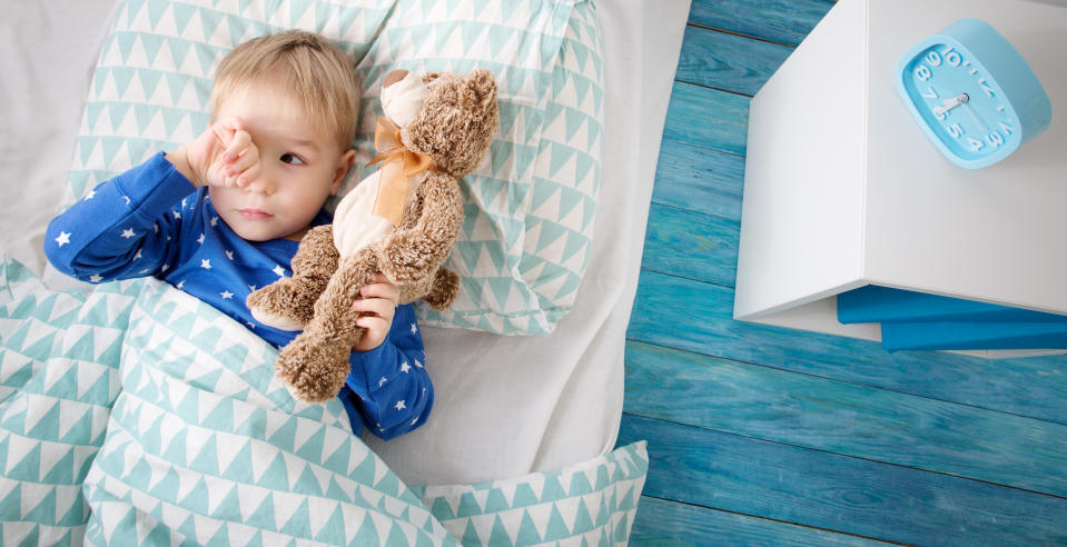 Three years old child crying in bed. Boy hiding and closing eyes with hands