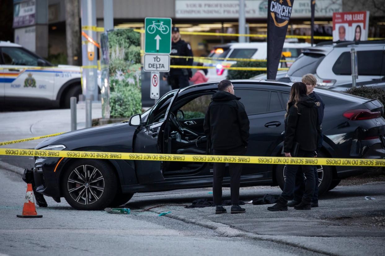 Investigators are pictured near a vehicle at the 8400 block of 120 Street after a shooting in Surrey on Friday. (Ben Nelms/CBC - image credit)