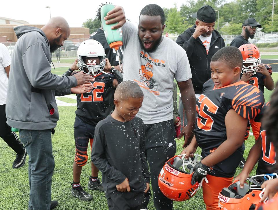 Akron Bengals coach, Jatone Stephens, includes his cousin Tyren Thompson, 7, as he douses his players with water to cool off during half time of their youth football game at Buchtel CLC in Akron. It was Tyren's first time back with the team since he was wounded in a shooting after a youth football game at Lane Field.