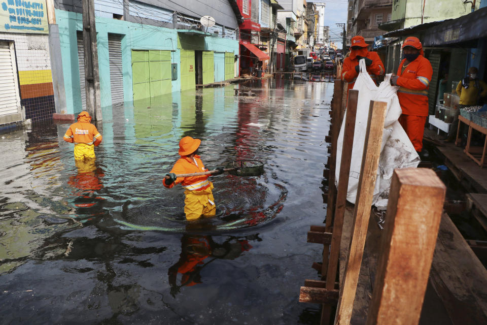 City workers pick trash from a street flooded by the waters of the Negro River in downtown Manaus, Brazil, Thursday, May 20, 2021. According to official records taken by the Port of Manaus, the city is facing one of its worse floods in years, with levels not seen since 1902, making it the second-worst flood ever recorded. (AP Photo/Edmar Barros)