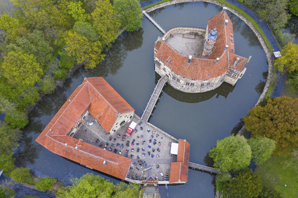 In this aerial view taken with a drone, around 100 spectators are seated during a concert as part of the Coesfeld model region at Burg Vischering, in L'dinghausen, Germany, Saturday, May 8, 2021. The circle presents the guitar virtuosos M. and T. Hoene. Admission was from 17:30 only with a negative coronavirus test. (Guido Kirchner/dpa via AP)