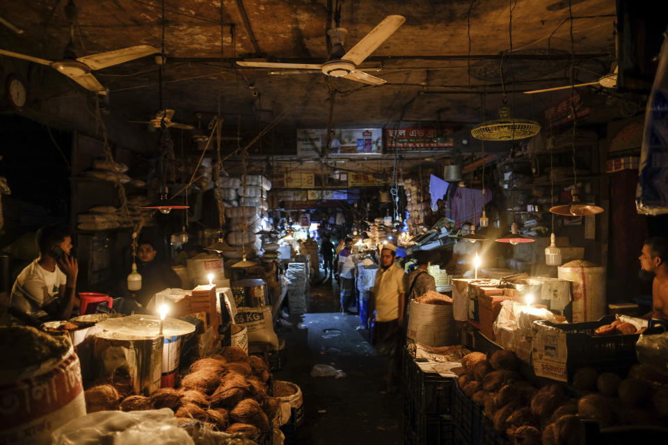 Shopkeepers light candles during power failure in Dhaka, Bangladesh Tuesday Oct. 4, 2022. A failure in Bangladesh's national power supply grid plunged most of the country into a blackout on Tuesday, officials said.(AP Photo/Mahmud Hossain Opu)