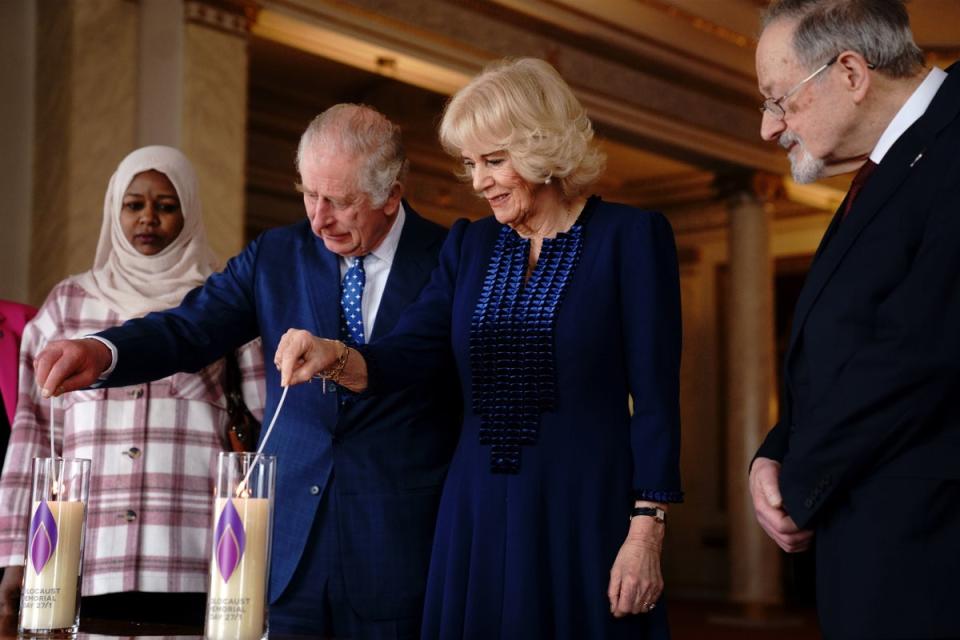 The King and the Queen Consort light a candle at Buckingham Palace to mark Holocaust Memorial Day (PA)