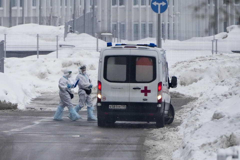 Medical workers walk to an ambulance at a hospital in Kommunarka, outside Moscow, Russia, Sunday, Jan. 23, 2022. Daily new coronavirus infections in Russia have reached an all-time high and authorities are blaming the highly contagious omicron variant, which they expect to soon dominate the country's outbreak. (AP Photo/Alexander Zemlianichenko)