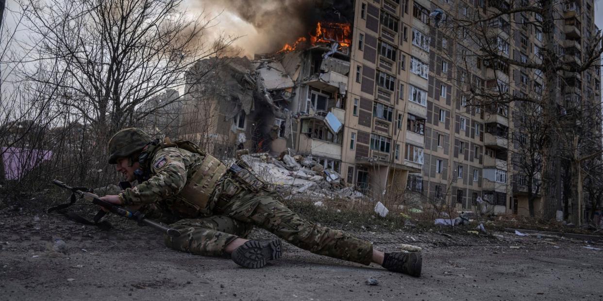 A Ukrainian police officer takes cover in front of a burning building that was hit in a Russian airstrike in Avdiivka, Ukraine, Friday, March 17, 2023.