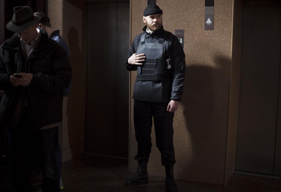 In this photo taken Friday, March 7, 2014, a Right Sector member stands guard next to elevators on the ground floor of the Dnipro hotel near the Independence Square, Kiev, Ukraine. The vocal and well-armed organization presents a headache for the new Ukrainian leadership with its armed presence in the streets, its radical nationalist rhetoric and its antics. (AP Photo/David Azia)