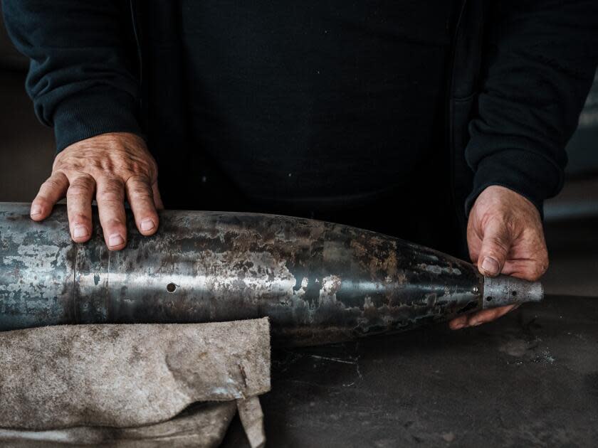 Artist Mikhail Reva examines a spent munition case. His sculptures are made from equal parts metal and rage.