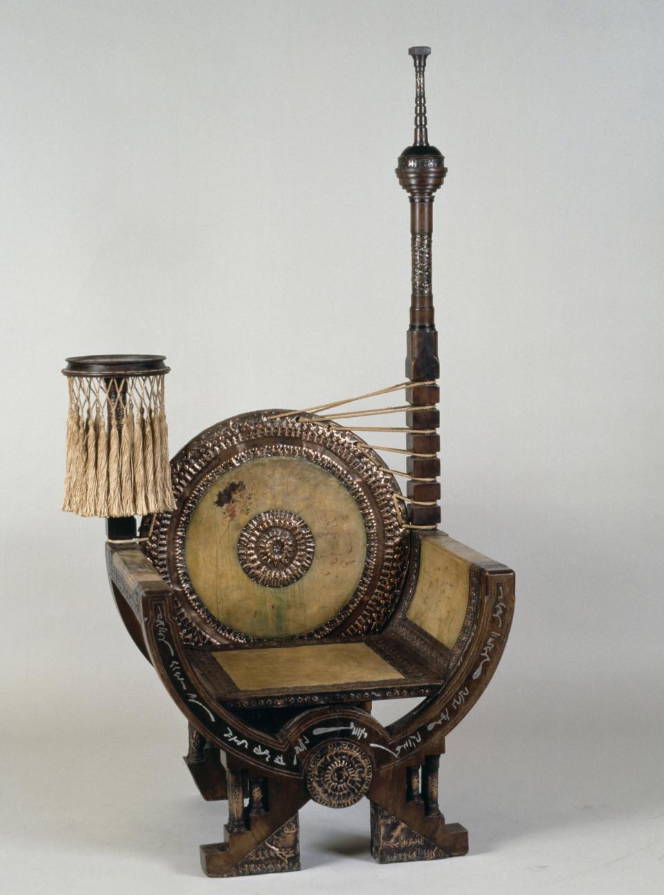 Designed in an African-inflected Art Nouveau style with a circular seat festooned with dense, tufted tassels and asymmetrical mini totems, this exuberant assemblage could serve as a throne for a fashionable prince. Perceived as as risibly tacky in the 1960s, Bugatti-designed throne chairs are now a sought-after item at auction.