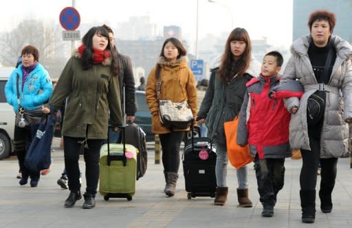 This file photo shows Chinese migrant workers and students preparing to board their trains home for the annual Chinese New Year holidays, in Beijing, in January. Migrant workers, who are among the lowest-paid in the country, have seen salary raises of 14.9% for an average of 2,200 yuan a month