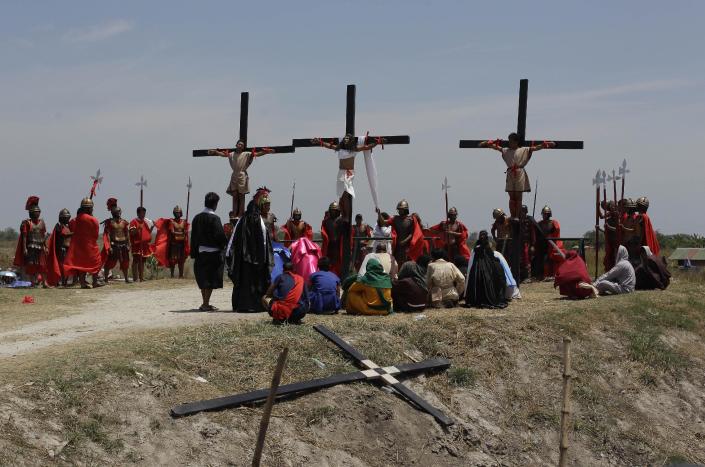 Filipino devotee Ruben Enaje, center, stays nailed to a cross with two actors during a play to re-enact the crucifixion of Jesus Christ in San Pedro Cutud village, Pampanga province, northern Philippines on Friday, April 18, 2014. Church leaders and health officials have spoken against the practice which mixes Roman Catholic devotion with folk belief, but the annual rites continue to draw participants and huge crowds. (AP Photo/Aaron Favila)