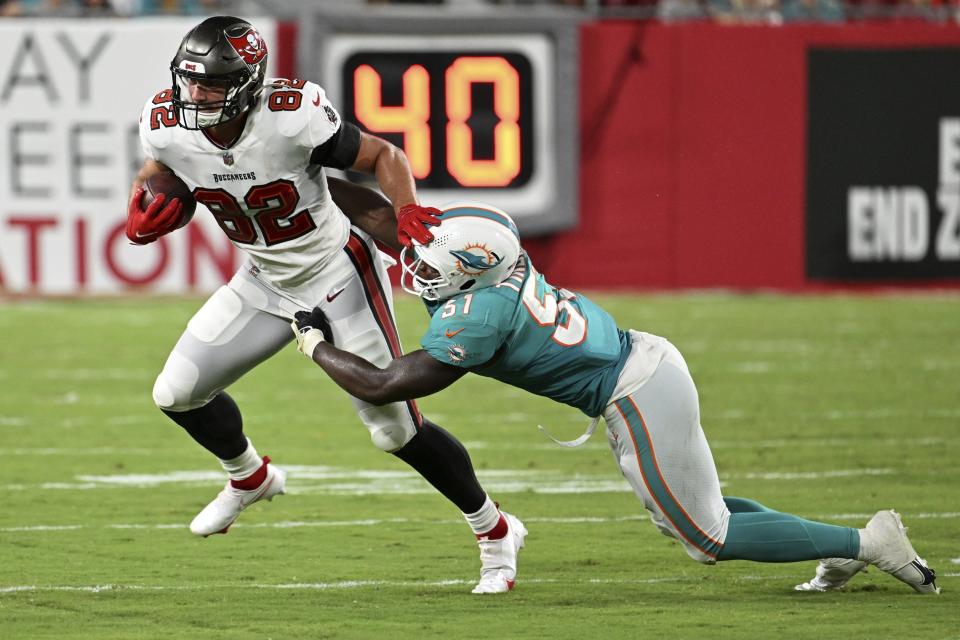 Tampa Bay Buccaneers tight end JJ Howland is stopped by Miami Dolphins linebacker Channing Tindall. [JASON BEHNKEN/AP]