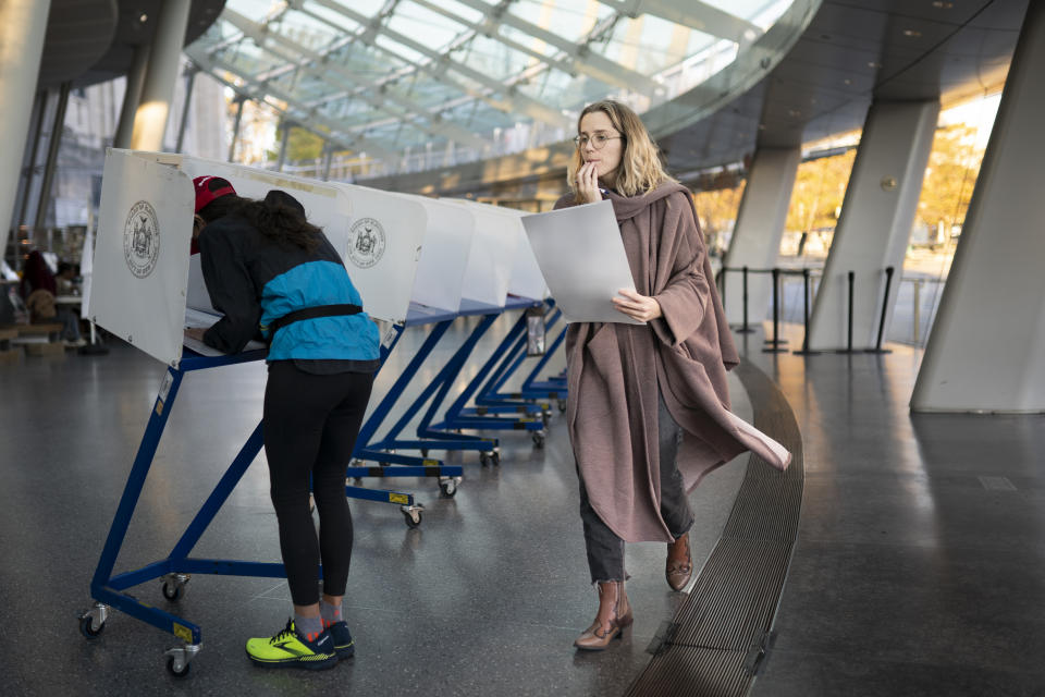 A voter moves to cast her ballot at an electronic counting machine at a polling site in the Brooklyn Museum, Tuesday, Nov. 8, 2022, in the Brooklyn borough of New York. (AP Photo/John Minchillo)