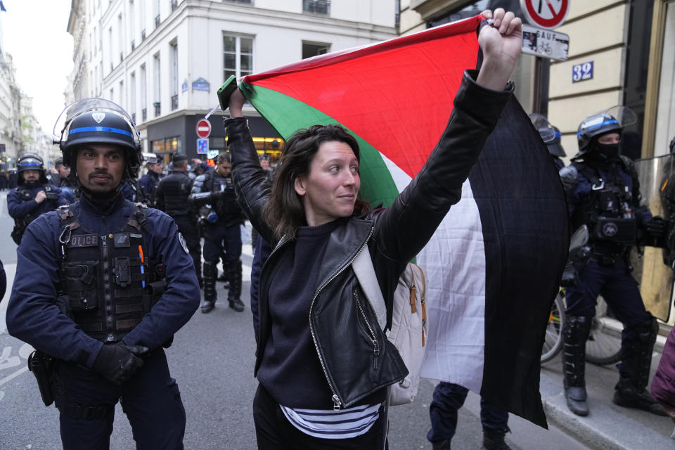 A woman holds a Palestine flag near Sciences-Po university in Paris Friday, April 26, 2024. Students in Paris inspired by Gaza solidarity encampments at campuses in the United States blocked access to a campus building at a prestigious French university Friday, prompting administrators to move all classes online. The pro-Palestinian protest at the Paris Institute of Political Studies, known as Sciences Po, came two days after police broke up a separate demonstration at one of the university's amphitheaters. (AP Photo/Michel Euler)