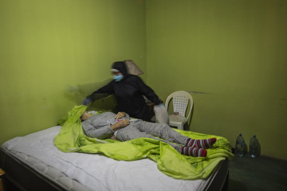 A woman covers with a bed sheet the face of her deceased mother-in-law suspected of dying from the new coronavirus, in Lima, Peru, Thursday, May 14, 2020. With more than half of COVID-19 cases going uncounted, the true scope of the disaster could be even worse, according to some doctors. (AP Photo/Rodrigo Abd)