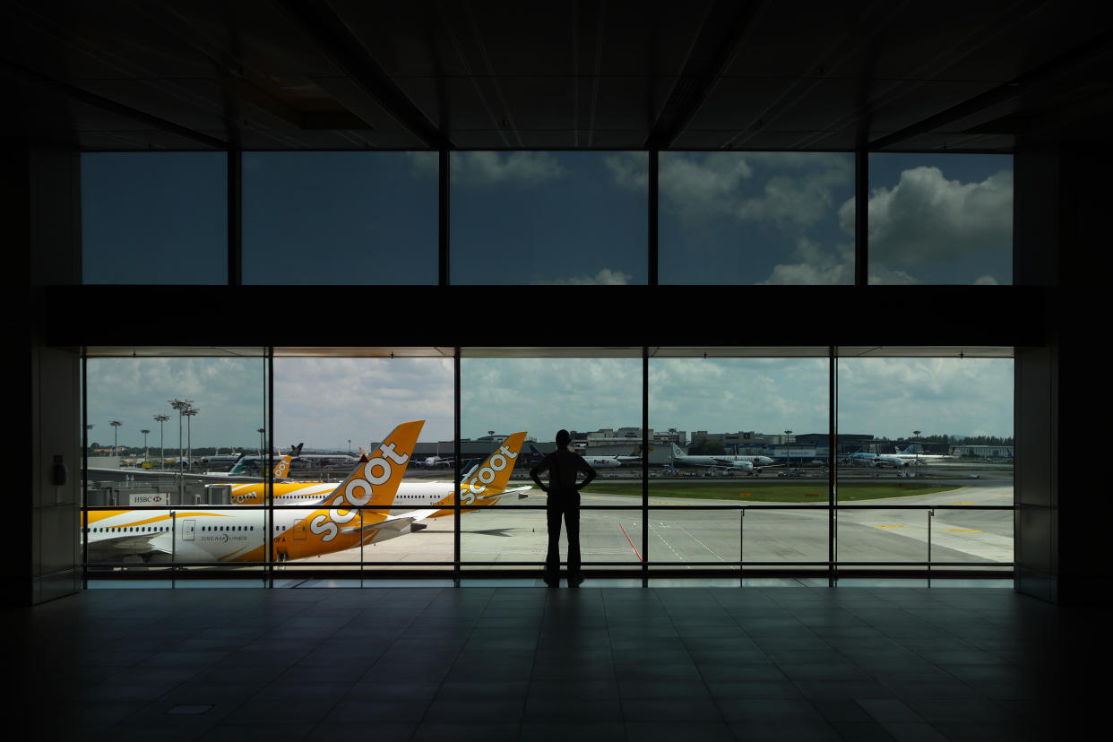 SINGAPORE - MARCH 24:  A man looks at Scoot aircrafts sitting on the tarmac at Changi Airport on March 24, 2020 in Singapore. Singapore Airlines will cut its capacity by 96% till the end of April as border restrictions tighten worldwide due to the spread COVID-19 pandemic.  (Photo by Suhaimi Abdullah/Getty Images)