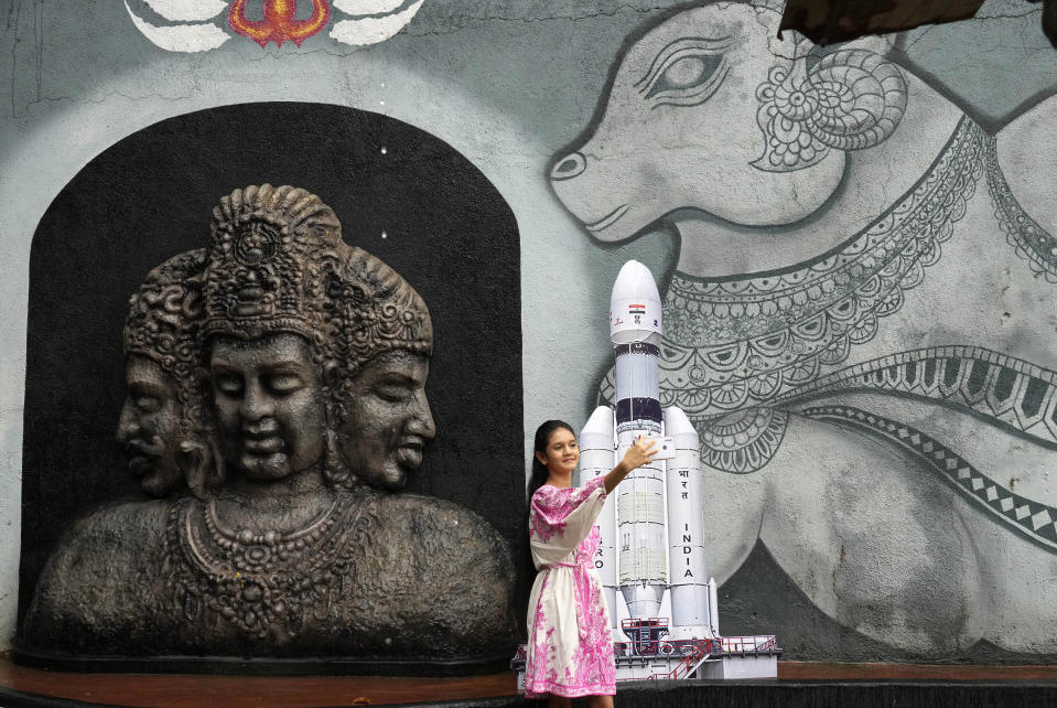 A girl takes a selfie with the Indian spacecraft Chandrayaan-3, the word for "moon craft" in Sanskrit, inside a temple in Mumbai, India, Friday, July 14, 2023. The Indian spacecraft blazed its way to the far side of the moon Friday in a follow-up mission to its failed effort nearly four years ago to land a rover softly on the lunar surface, the country's space agency said. (AP Photo/Rajanish Kakade)