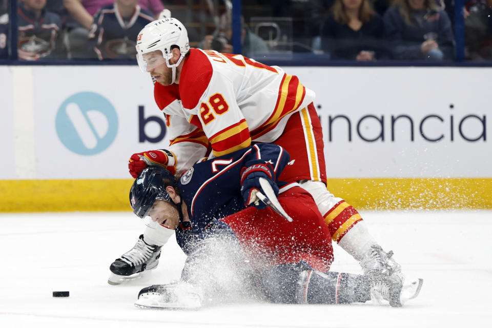CORRECTS TO DAMON SEVERSON NOT DAMON SEVERSON BLACK - Calgary Flames forward Elias Lindholm, top, collides with Columbus Blue Jackets' Damon Severson, bottom, during the first period of an NHL hockey game in Columbus, Ohio, Friday, Oct. 20, 2023. (AP Photo/Paul Vernon)