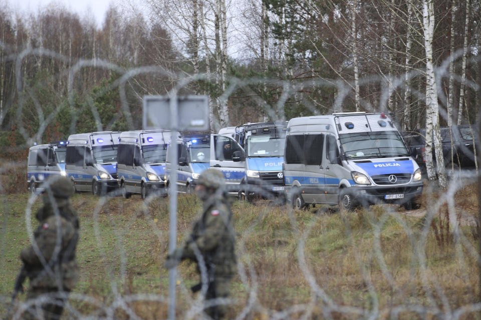 Polish border guards behind barbed wire as migrants from the Middle East and elsewhere gather at the Belarus-Poland border near Grodno, Belarus, Monday, Nov. 8, 2021. Poland increased security at its border with Belarus, on the European Union's eastern border, after a large group of migrants in Belarus appeared to be congregating at a crossing point, officials said Monday. The development appeared to signal an escalation of a crisis that has being going on for months in which the autocratic regime of Belarus has encouraged migrants from the Middle East and elsewhere to illegally enter the European Union, at first through Lithuania and Latvia and now primarily through Poland. (Leonid Shcheglov/BelTA via AP)