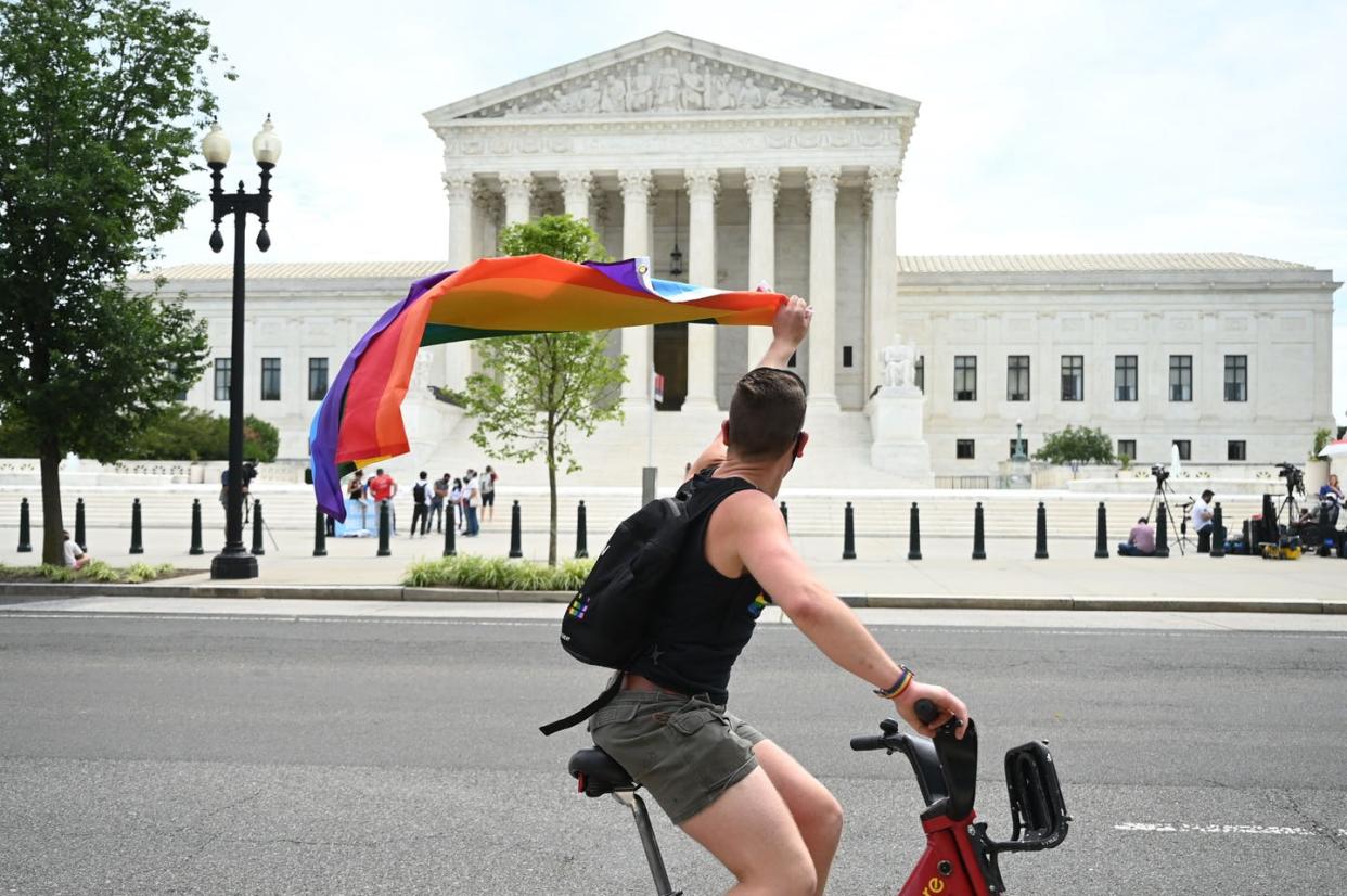 <span class="caption">A man waves a rainbow flag as he rides by the Supreme Court on June 15, 2020.</span> <span class="attribution"><a class="link " href="https://www.gettyimages.com/detail/news-photo/man-waves-a-rainbow-flag-as-he-rides-by-the-us-supreme-news-photo/1220208273?adppopup=true" rel="nofollow noopener" target="_blank" data-ylk="slk:JIM WATSON/AFP via Getty Images;elm:context_link;itc:0;sec:content-canvas">JIM WATSON/AFP via Getty Images</a></span>