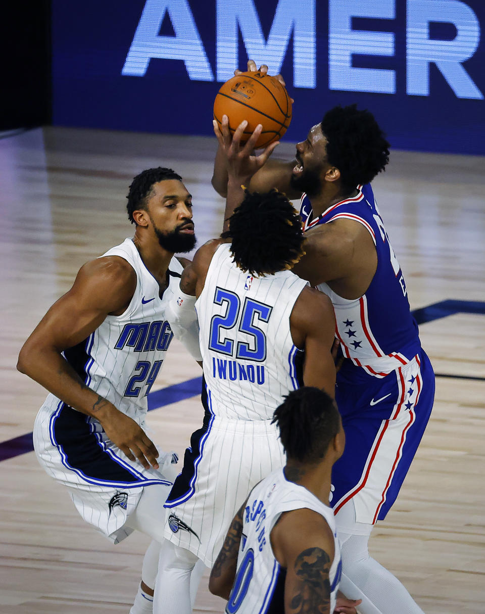 Philadelphia 76ers' Joel Embiid (21) scores against Orlando Magic's Khem Birch (24) and Wes Iwundu (25) during the second half of an NBA basketball game Friday, Aug. 7, 2020, in Lake Buena Vista, Fla. (Kevin C. Cox/Pool Photo via AP)