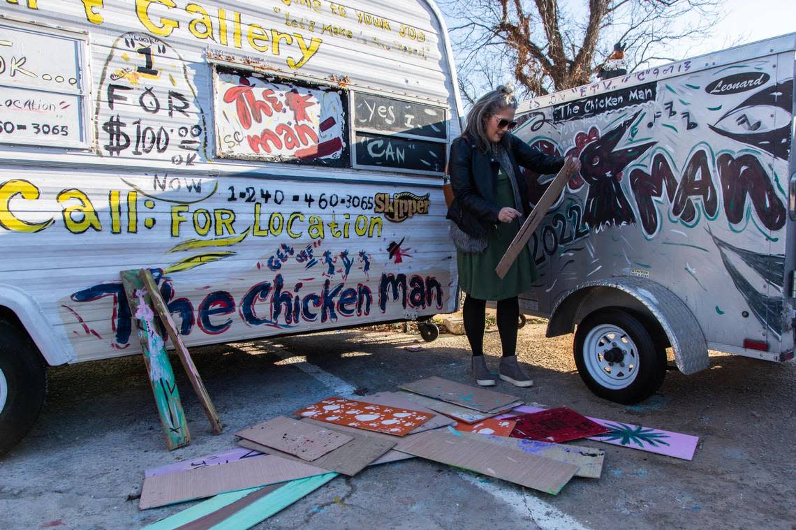 Paige Stiles looks at paintings by Ernest Lee, more commonly known as the Chicken Man, at his corner of Gervais Street on Friday, December 15, 2022. Stiles already has many of his paintings of her own, and is shopping for gifts for friends.