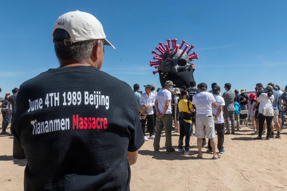 Visitors gather at Chinese artist Weiming Chen’s unveiling ceremony for his replacement CCP Virus II sculpture at his Liberty Sculpture Park in Yermo on June 5, 2022. His original anti-COVID-19 and anti-communist sculpture was burned after it was unveiled in 2021.