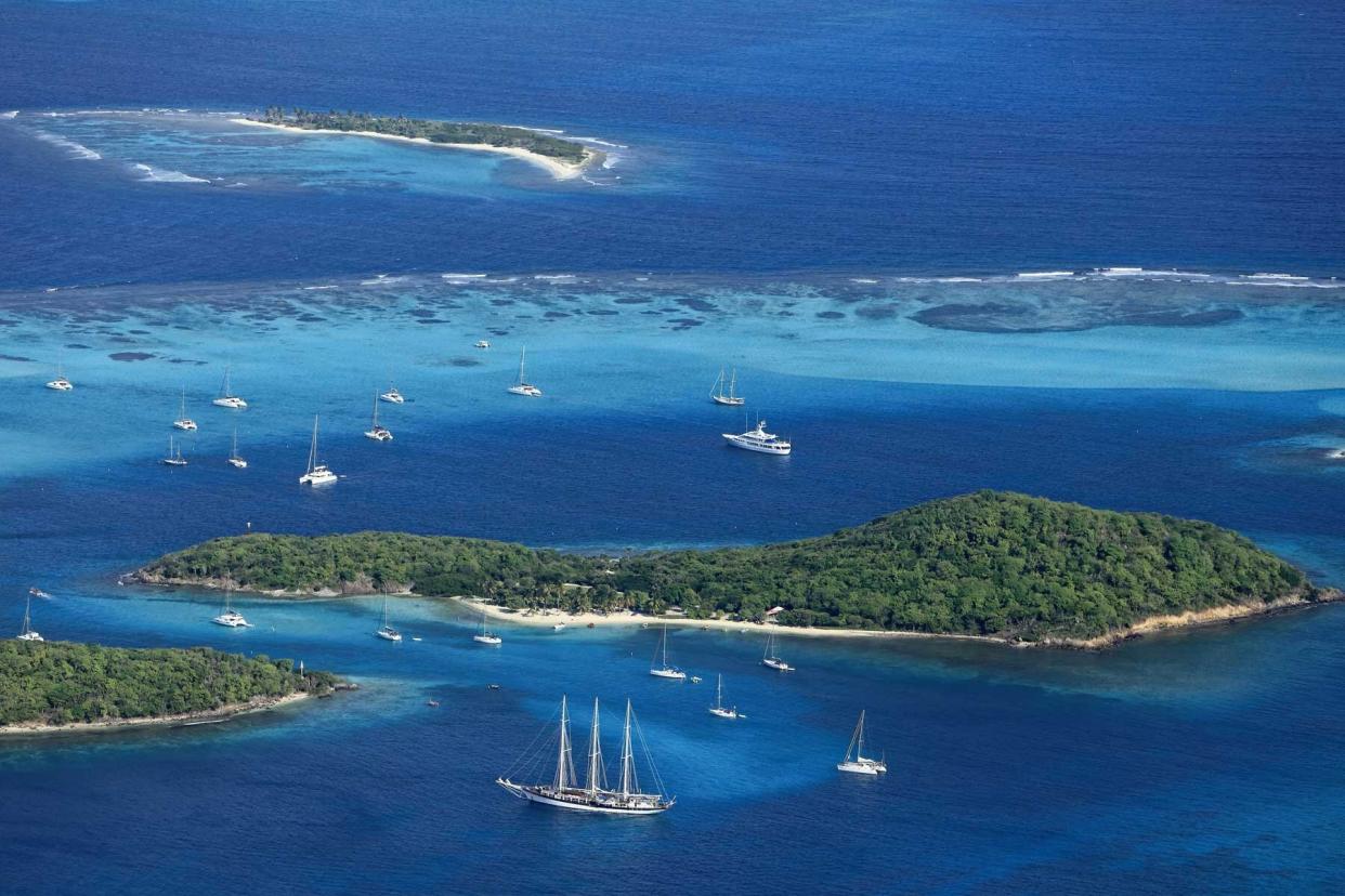 Caribbean, Saint Vincent and the Grenadines: aerial view of the small group of islands of the archipelago of Tobago Cays in the heart of the Tobago Cays Marine Park, with catamarans, a yacht and a three-masted ship in the turquoise waters.