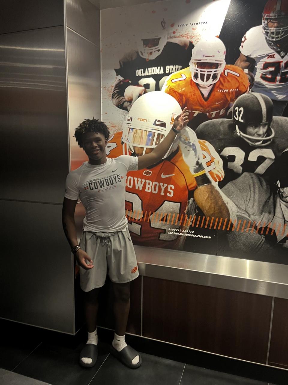 Tatum Bell Jr. poses in front of a portrait of his father, former Oklahoma State running back Tatum Bell Sr., inside the OSU football facility.