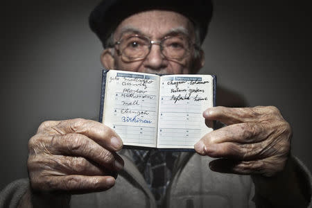 90 year old holocaust survivor Hy Abrams poses for a portrait with a book that he carries with him everyday that documents all the different concentration camps he was held in during the second World War, in the Brooklyn borough of New York January 15, 2015. REUTERS/Carlo Allegri