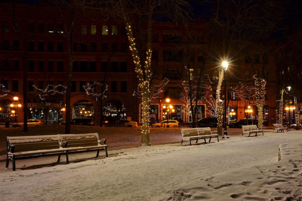 A street decorated in Christmas lights and covered in snow. 