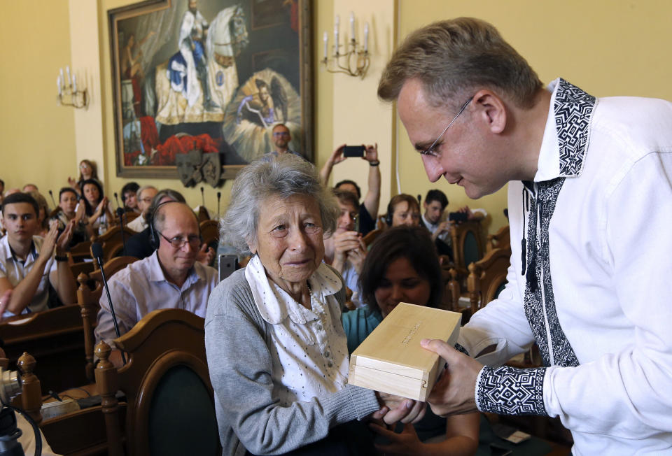 Lviv Mayor Andriy Sadoviy, right, presents a glass copy of an old metal synagogue key to Yanina Hescheles, Polish writer and a Nazi concentration camp survivor, at a ceremony commemorating the 75th anniversary of the annihilation of the city's Jewish population by Nazi Germany in Lviv, Ukraine, Sunday, Sept. 2, 2018. The Ukrainian city of Lviv, once a major center of Jewish life in Eastern Europe, is commemorating the 75th anniversary of the annihilation of the city's Jewish population by Nazi Germany and honoring those working today to preserve that vanished world. The commemoration comes amid a larger attempt in Ukraine to preserve the memories of the prewar Jewish community. (AP Photo/Yevheniy Kravs)