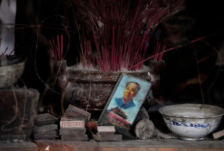 A card featuring the late Chinese Chairman Mao Zedong and Tiananmen Gate is seen next to a shrine in the old dwelling of surviving villager Wang Guocheng, at a minority village destroyed in the 2008 Sichuan earthquake in Wenchuan county, Sichuan province, China, April 5, 2018. REUTERS/Jason Lee