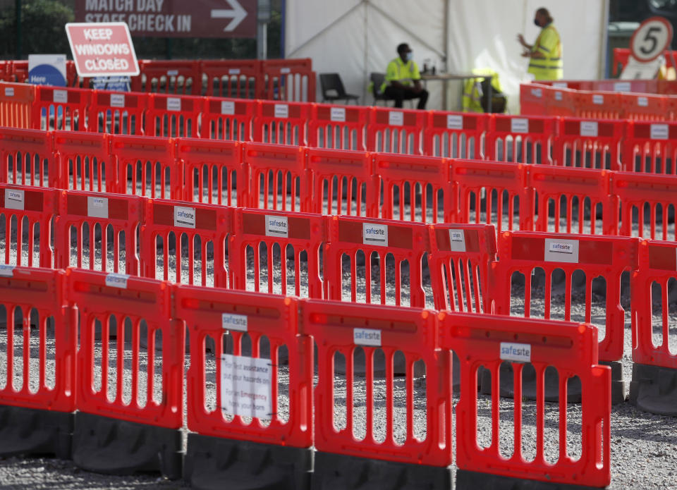 Staff members wait beside empty lanes of a Covid-19 drive thru testing facility at Twickenham stadium in London, Thursday, Sept. 17, 2020. Britain has imposed tougher restrictions on people and businesses in parts of northeastern England as the nation attempts to stem the spread of COVID-19, although some testing facilities remain under-utilised. (AP Photo/Frank Augstein)