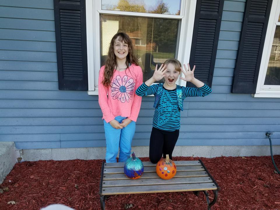 Alex and Wendy Schwabe pose in front of pumpkins they painted for Halloween, including one to participate in the Teal Pumpkin Project, to support children with food allergies.