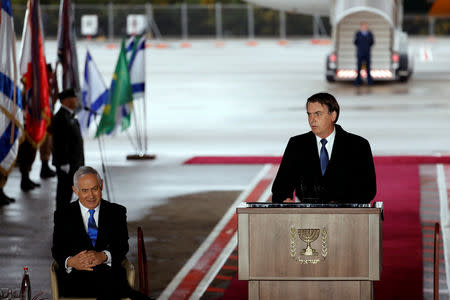 Brazilian President Jair Bolsonaro speaks as Israeli Prime Minister Benjamin Netanyahu sits nearby during a welcoming ceremony upon his arrival in Israel, at Ben Gurion International airport in Lod, near Tel Aviv, Israel March 31, 2019. REUTERS/Ronen Zvulun