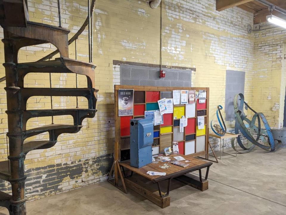 A spacious room at Old Bakery Beer holds an eclectic grouping of art, memorabilia and other items. This view shows a notice board, sculptures and a glimpse of an old spiral staircase.