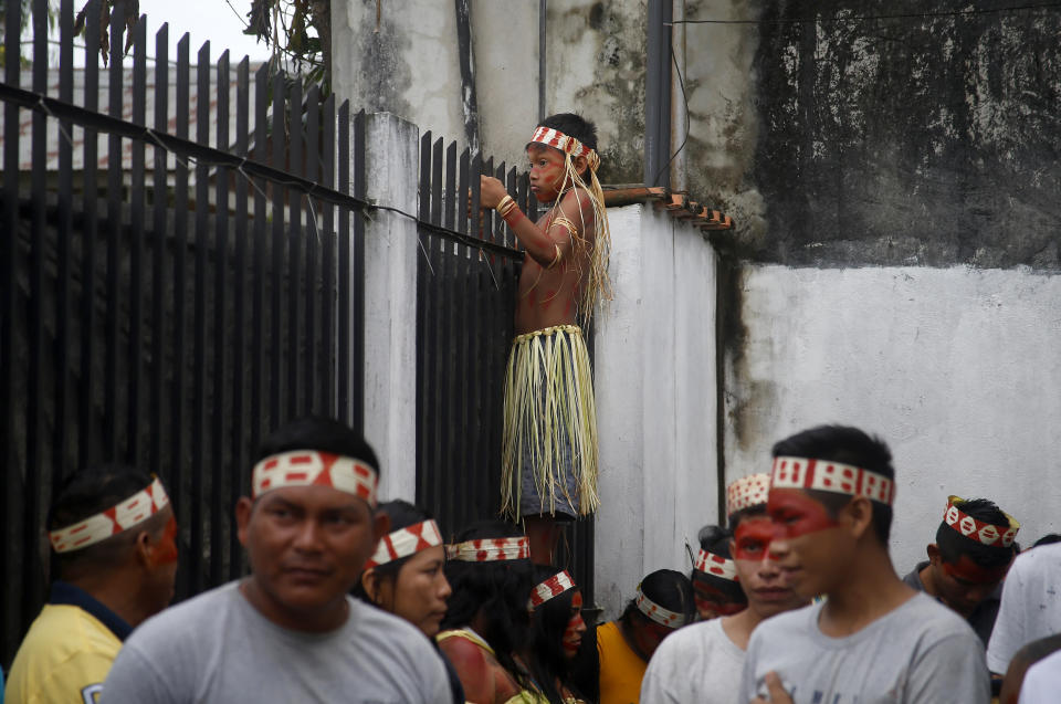 A Mayuruna Indigenous boy climbs a fence to look at the march against the disappearance of Indigenous expert Bruno Pereira and freelance British journalist Dom Phillips, in Atalaia do Norte, Vale do Javari, Amazonas, state Brazil, Monday, June 13, 2022. Brazilian police are still searching for Pereira and Phillips, who went missing in a remote area of Brazil's Amazon a week ago. (AP Photo/Edmar Barros)