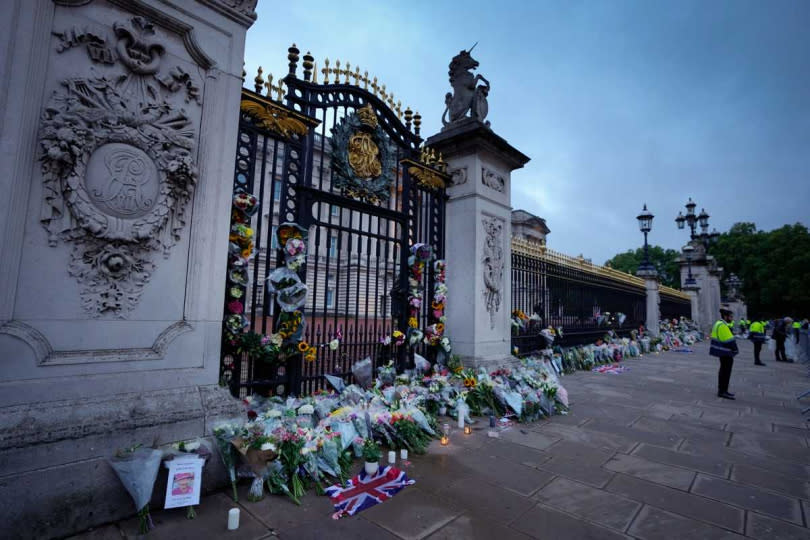英國民眾在白金漢宮外圍擺放鮮花與物品悼念女王。（圖／達志／美聯社）
