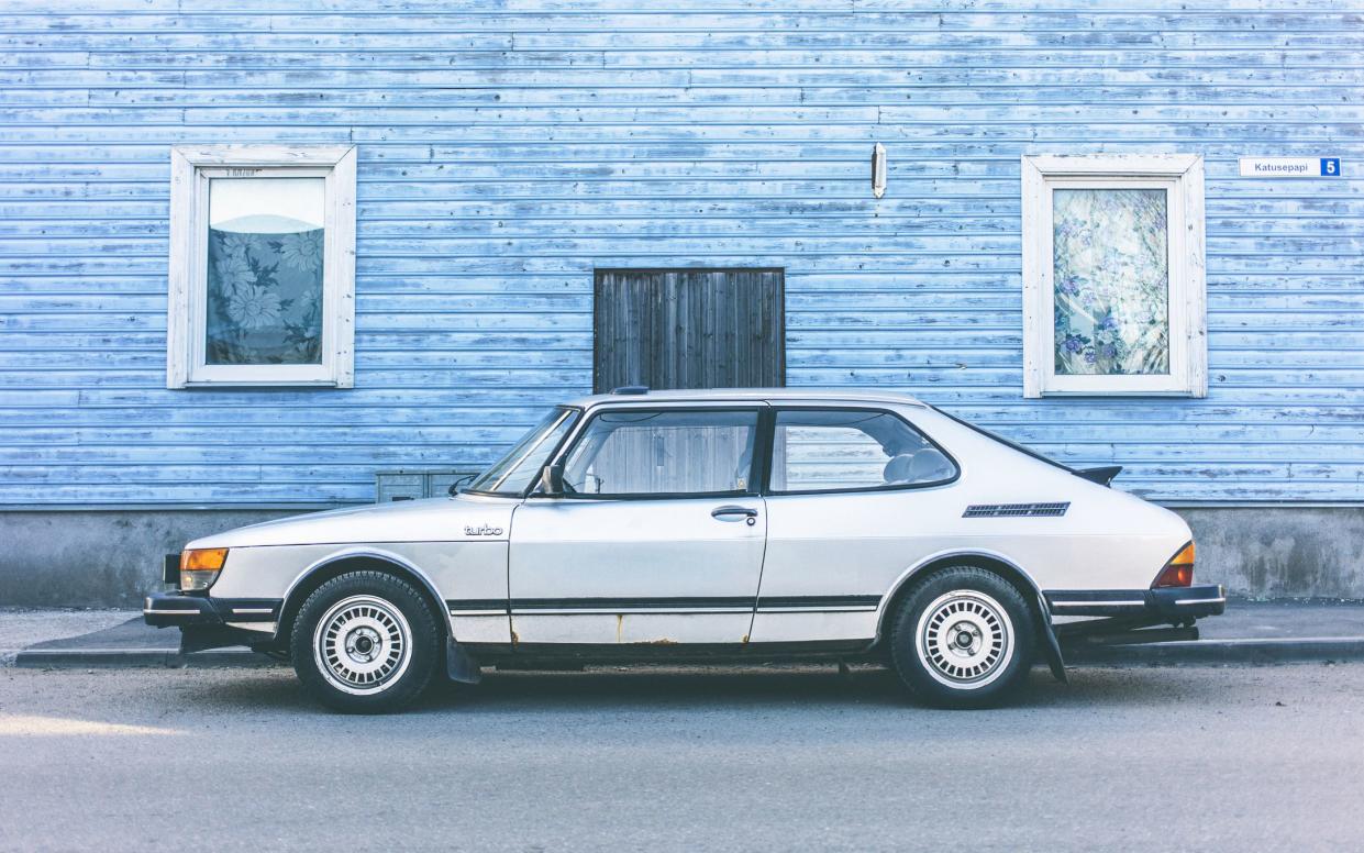 Tallinn, Estonia - May 1, 2013: Early 80s classic Saab 900 Turbo parked on town street in front of blue wooden house.