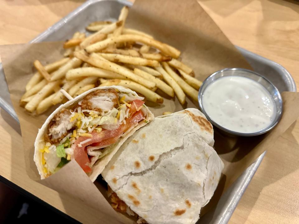 Crispy chicken wrap with french fries on parchment paper on metal tray