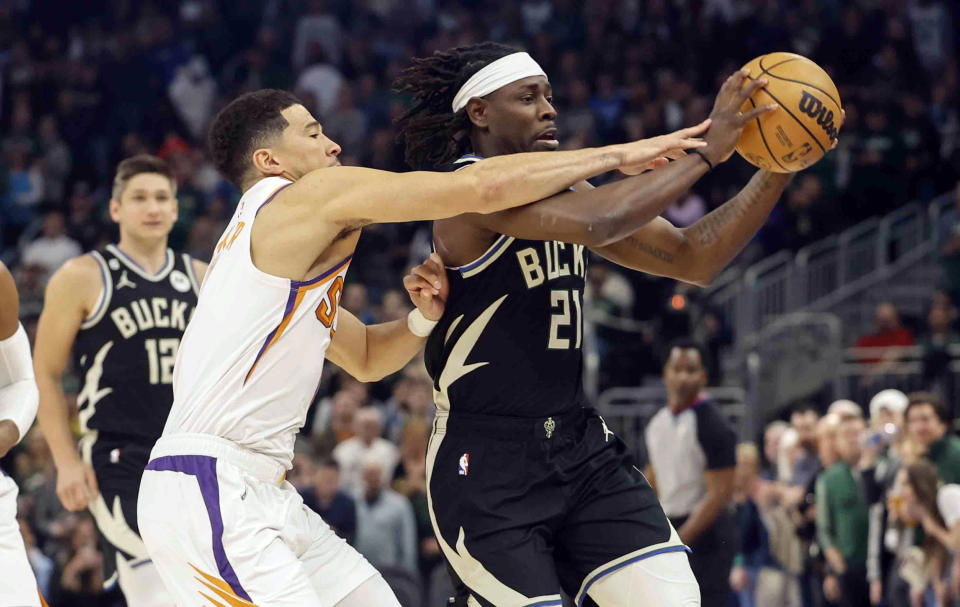 Phoenix Suns guard Devin Booker (1) reaches in on Milwaukee Bucks guard Jrue Holiday (21) during the first half of an NBA basketball game Sunday, Feb. 26, 2023, in Milwaukee. (AP Photo/Jeffrey Phelps)