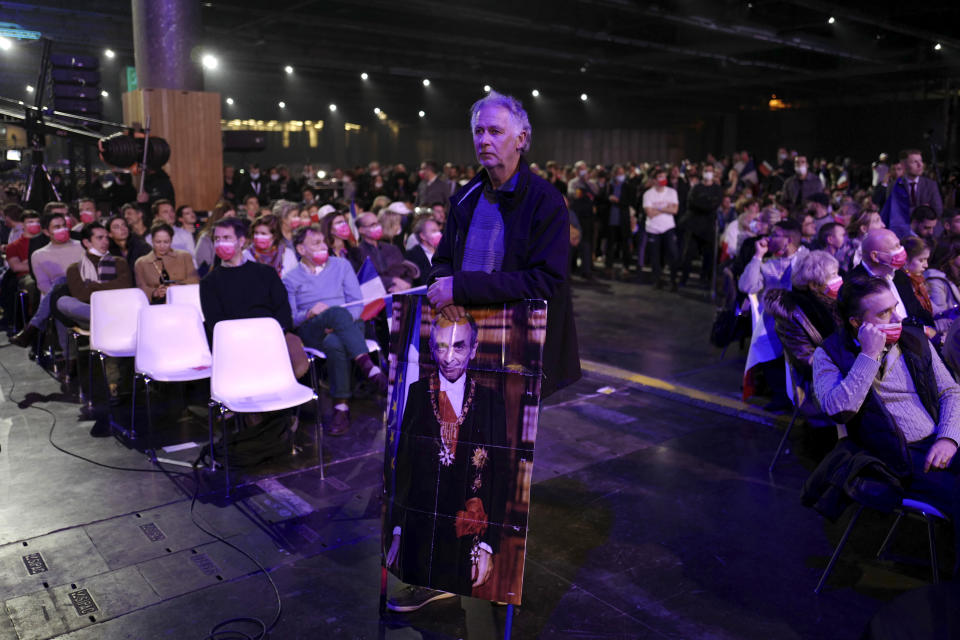 A supporter of French far right presidential candidate Eric Zemmour holds a portrait of Zemmour dressed like the French President during his first rally, Sunday, Dec. 5, 2021 in Villepinte, north of Paris. Far-right former French TV pundit Eric Zemmour is holding his first campaign rally, a few days after he formally declared his candidacy for April's presidential election in a video relaying his anti-migrants, anti Islam views. A first round is to be held on April, 10, 2022 and should no candidate win a majority of the vote in the first round, a runoff will be held between the top two candidates on April 24, 2022. (AP Photo/Rafael Yaghobzadeh)