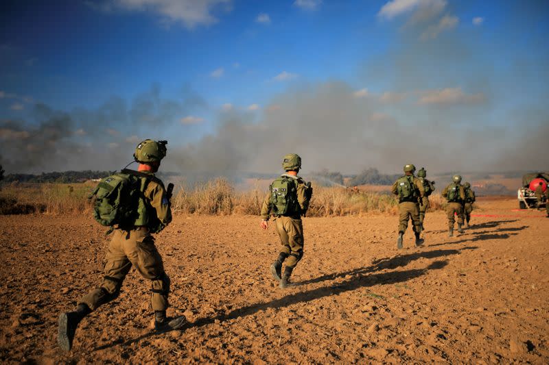 Israeli soldiers try to extinguish fire, on the Israeli side of the border between Israel and the Gaza Strip