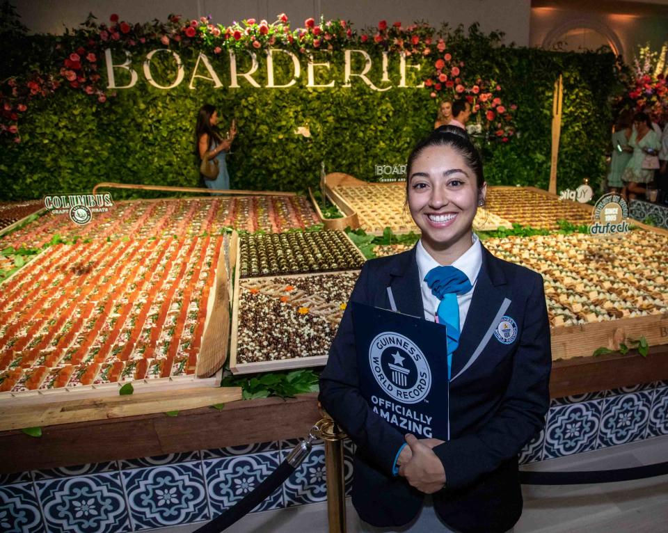 Guinness World Records adjudicator, Chrissy Fernandez, stands next to the largest charcuterie board in the world at The Colony Hotel in Palm Beach. It was created by Riviera Beach-based Boarderie.